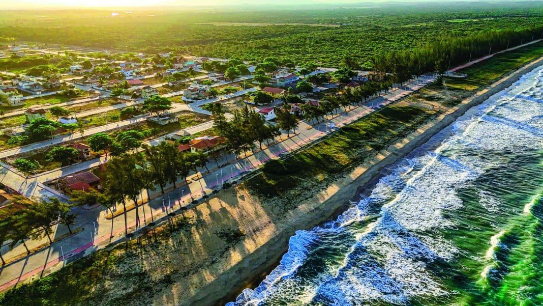 Vista aérea da orla de Presidente Kennedy ao entardecer, com a avenida arborizada à beira da praia