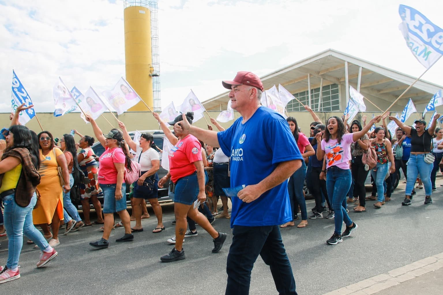 Marcão caminhando na rua ao lado de apoiadores com bandeiras da campanha